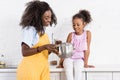 happy african american mother and daughter cooking