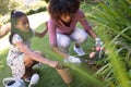 Happy african american mother with daughter outdoors, gardening on sunny day Royalty Free Stock Photo