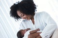 Happy African American Mother holding her newborn infant baby while sitting on bed in hospital. Mother hand lulling little child Royalty Free Stock Photo