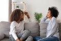 Happy African American mother and teen daughter chatting at home