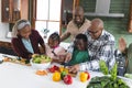 Happy african american multi generation family chopping vegetables in kitchen, slow motion Royalty Free Stock Photo