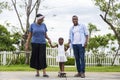 Happy African American parent teach his little daughter to play skateboard in the public park during summer for family leisure tim