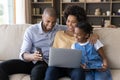 Happy African American parents and daughter kid resting on couch Royalty Free Stock Photo