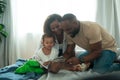 Happy African American Parents with little daughters playing , reading book on the bed in bedroom at home, happy family concept Royalty Free Stock Photo