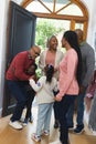 Happy african american parents, son and daughter welcoming grandparents at front door