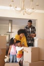 Happy African American parents with their children packing their belongings in living room