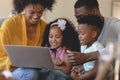 Happy African American parents with their cute children using laptop on sofa Royalty Free Stock Photo