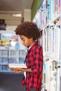 Happy african american schoolboy reading book standing in school library Royalty Free Stock Photo