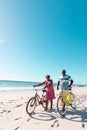 Happy african american senior couple with bicycles walking at beach under clear sky during vacation Royalty Free Stock Photo