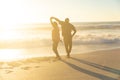 Happy african american senior couple dancing on shore at beach during sunset Royalty Free Stock Photo