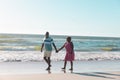 Happy african american senior couple holding hands and walking at seashore under clear sky Royalty Free Stock Photo