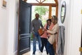 Happy african american senior mother welcoming adult daughter with husband at front door Royalty Free Stock Photo