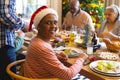 Happy african american senior woman celebrating with friends at christmas dinner in dining room Royalty Free Stock Photo