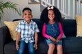 Happy african american siblings sitting on sofa and looking at camera Royalty Free Stock Photo
