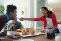 Happy african american son and father sitting at table during breakfast, daughter feeding him Royalty Free Stock Photo