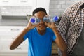 Happy african american son sorting recycling with father in kitchen, playing with plastic bottles Royalty Free Stock Photo