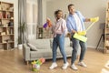 Happy african american spouses having fun with mop and detergent bottle, singing while cleaning house Royalty Free Stock Photo