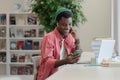 Happy African American student guy using mobile device while studying in library Royalty Free Stock Photo