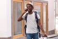 Happy african american tourist walking with mobile phone and bags through city Royalty Free Stock Photo