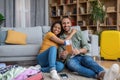 Happy african american tourists couple holding passport with tickets and embracing, packing suitcases at home