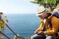 Happy african american travel man sitting by sea looking at mobile phone Royalty Free Stock Photo