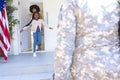 Happy african american wife and daughter welcoming male soldier outdoors with usa flag, copy space