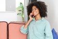 Happy african-american woman chatting on the smartphone sitting on the sofa at home Royalty Free Stock Photo