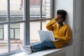 Happy African American woman freelancer with afro hairstyle working on laptop, talking in video chat, laughing with toothy smile. Royalty Free Stock Photo