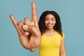 Happy African American woman gesturing big rock sign, looking and smiling at camera over blue studio background Royalty Free Stock Photo