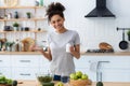 Happy african american woman in home kitchen holding bottle of nutritional supplements Royalty Free Stock Photo