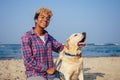 Happy african american woman hugging her dog in tropical beach