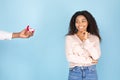 Happy african american woman looking at gift box with ring in man hand and smiling, standing on blue studio background Royalty Free Stock Photo