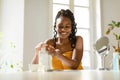 Happy african american woman pouring moisturising body lotion from bottle on hand, using new skincare product after bath Royalty Free Stock Photo