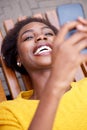 Happy african american woman sitting outside and looking at cellphone Royalty Free Stock Photo