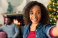 Happy african american woman taking selfie, christmas decorations in background Royalty Free Stock Photo