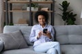 Happy African American woman use smartphone relaxing at home Royalty Free Stock Photo