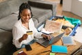 Happy african american woman using credit card and laptop, booking abroad trip, surfing online travel agency website Royalty Free Stock Photo