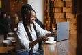 Happy african american woman worker using laptop work study at computer in loft office or cafe, smiling mixed race female student Royalty Free Stock Photo