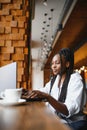 Happy african american woman worker using laptop work study at computer in loft office or cafe, smiling mixed race female student Royalty Free Stock Photo