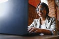 Happy african american woman worker using laptop work study at computer in loft office or cafe, smiling mixed race female student Royalty Free Stock Photo