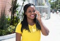 Happy african american woman in a yellow shirt at mobile phone Royalty Free Stock Photo