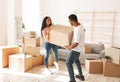 Happy African American woman and her husband carrying cardboard box with their possessions on relocation day Royalty Free Stock Photo