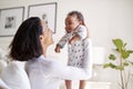 Happy African American young adult mother raising her three month old baby son in the air, smiling at him, close up