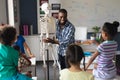 Happy african american young male teacher explaining skeleton to multiracial elementary students