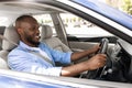 Smiling black guy driving new car in city Royalty Free Stock Photo