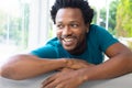 Happy african american young man looking away while sitting on sofa at home Royalty Free Stock Photo