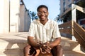 Happy African American young man sitting on stairs outdoors looking at camera. Royalty Free Stock Photo