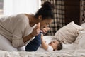 Loving biracial mother relax on bed play with little baby Royalty Free Stock Photo
