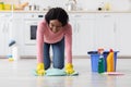 Happy african american young woman cleaning floor in kitchen Royalty Free Stock Photo