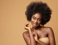 Happy African Beauty Model with Afro Hairstyle. Cheerful smiling Woman with Dark Skin and Black Coily Hair over Beige. Face Body Royalty Free Stock Photo